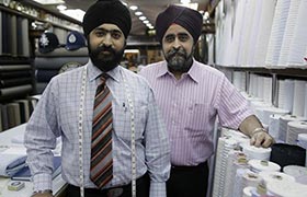 Master tailors Jesse and Victor pose in their shop