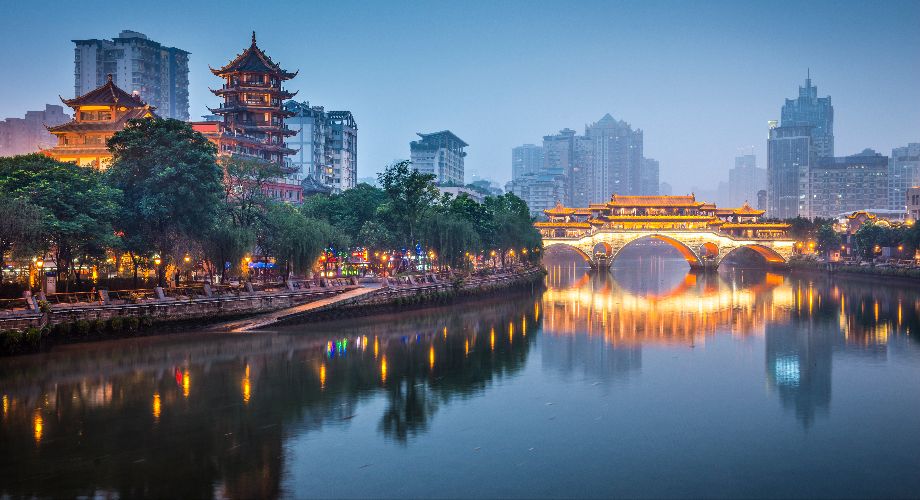 Edifícios e uma ponte sobre o rio Jin em Chengdu iluminada à noite