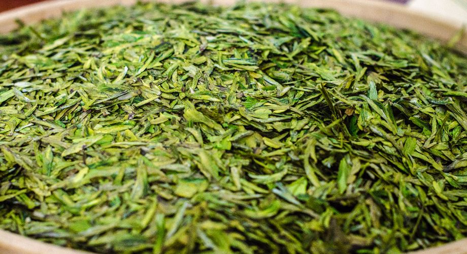 Hojas verdes secas de té longjing en una cesta, en Hangzhou