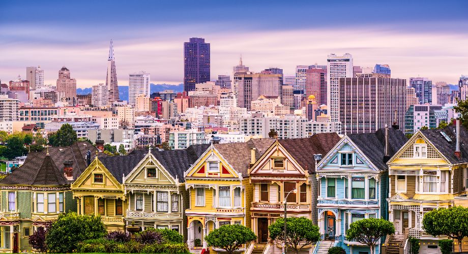 Farbenfrohe viktorianische Häuser in San Francisco mit der Stadt im Hintergrund