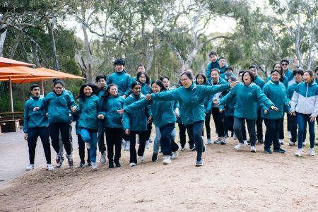 Group of "I can fly programme" student jumping in front of the plane 