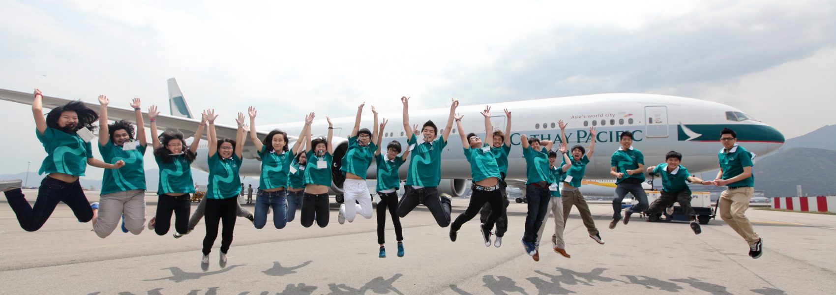 Group of "I can fly programme" student jumping in front of the plane 