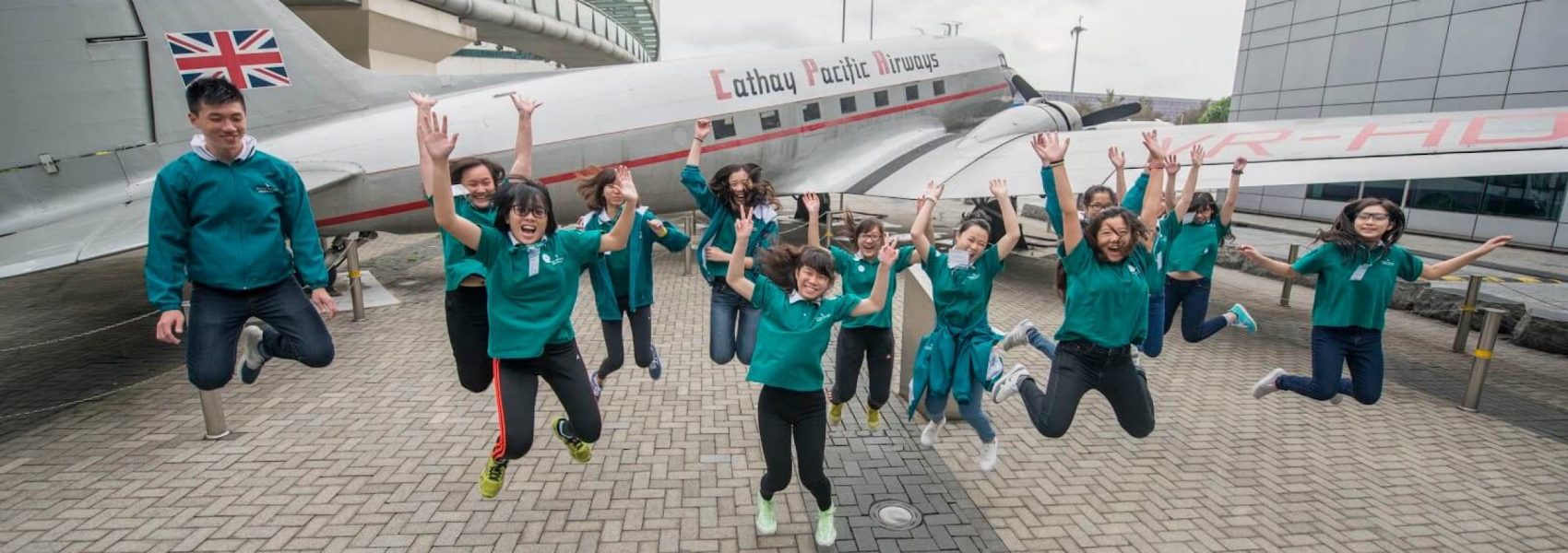 Group of "I can fly programme" student jumping in front of the plane 