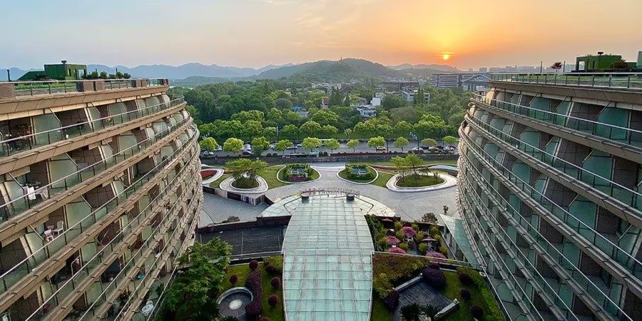 A panoramic view of a sunset from atop a building, with warm hues illuminating the horizon and cityscape below.