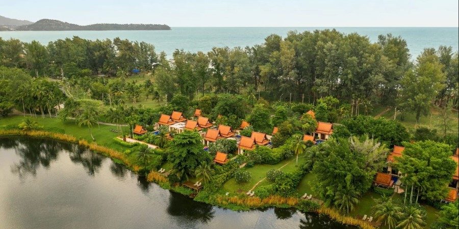 Aerial view of a resort surrounded by a lake and lush trees, showcasing the natural beauty of the landscape.