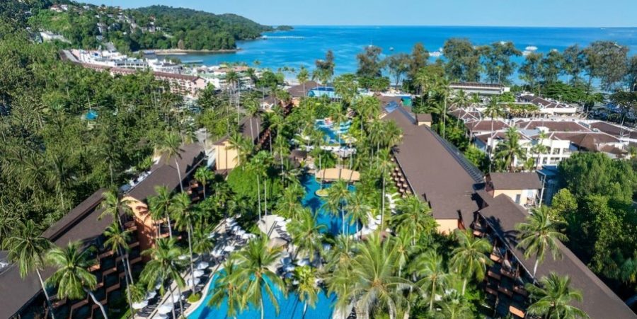 Aerial view showcasing a resort alongside a sandy beach and clear blue waters, highlighting the scenic coastal landscape.