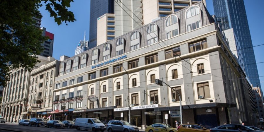 一座大型酒店建築，中央有一座時鐘塔，燈光柔和，營造出迷人氛圍。