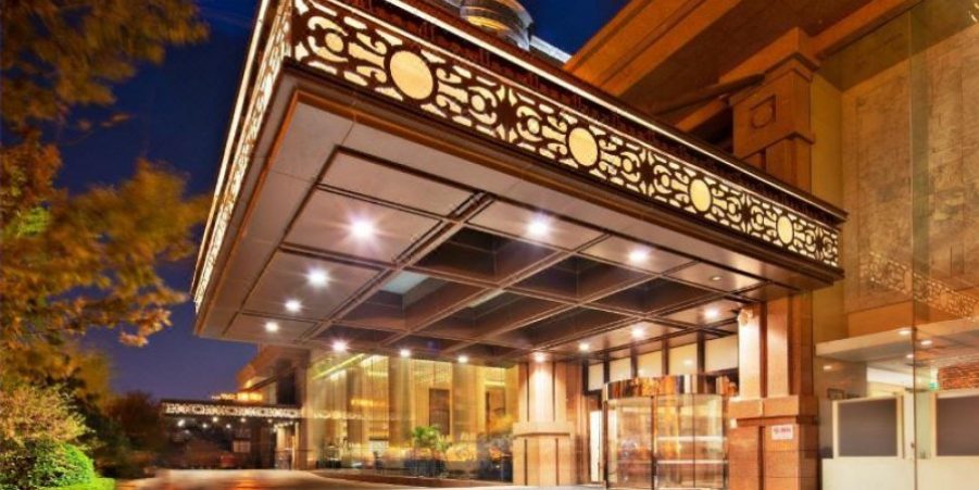 The illuminated front entrance of a hotel at night, showcasing elegant architecture and welcoming ambiance.