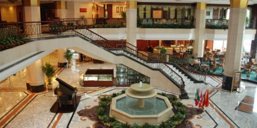 A spacious lobby featuring a central fountain and elegant stairs leading to an upper level.