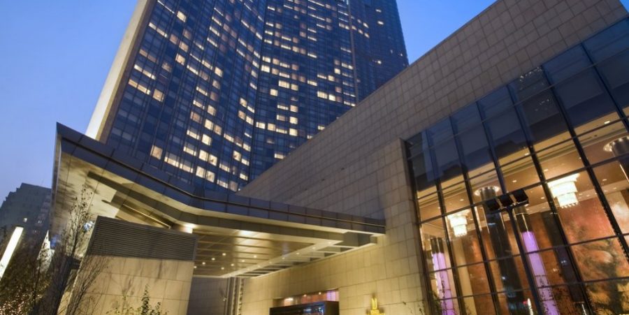The exterior of a hotel illuminated at night, showcasing its architecture and welcoming entrance.