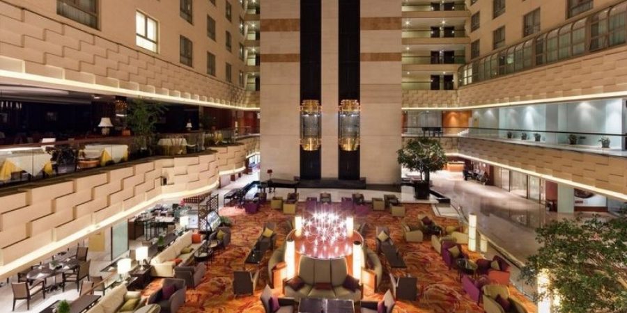 A spacious hotel lobby featuring a large atrium with natural light and elegant furnishings.