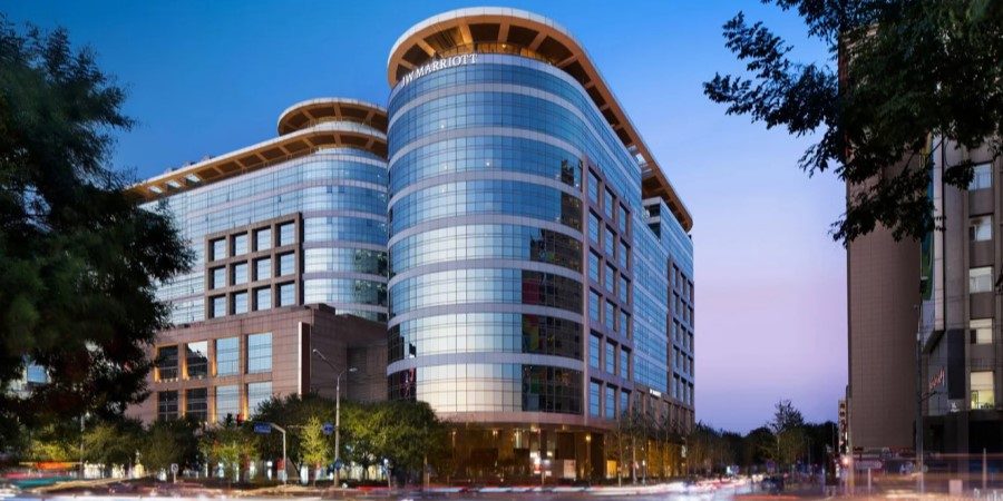 A modern glass building featuring a unique circular design, reflecting light and surrounding scenery.