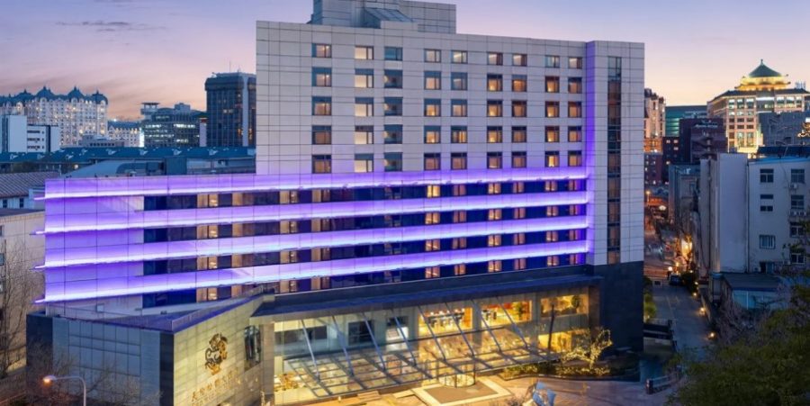 The hotel is illuminated in vibrant shades of purple and blue, creating a striking nighttime ambiance.