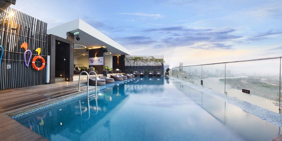 A large glass wall surrounds the hotel pool, offering an unobstructed view of the serene swimming area.