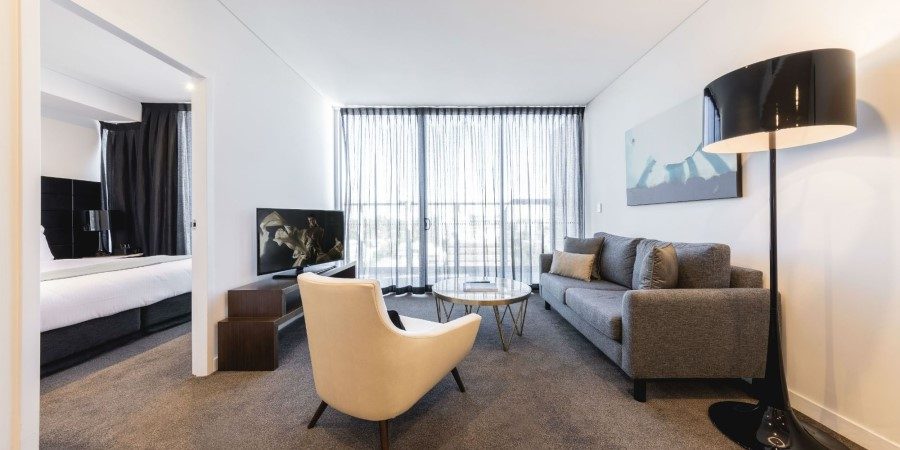 A modern hotel room featuring a couch, a chair, and a television, designed for comfort and relaxation.