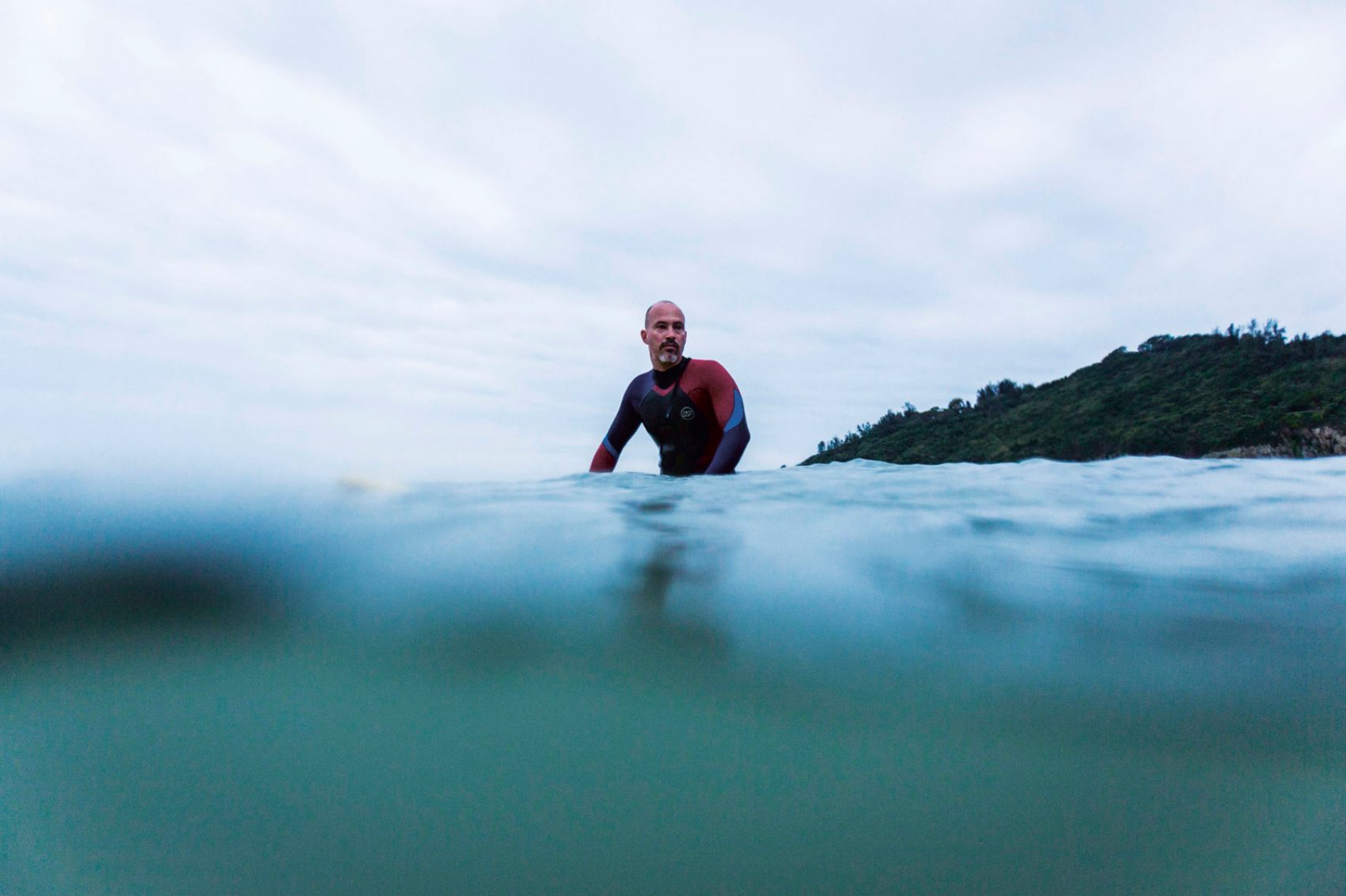 A diver runs into the water of Big Wave Bay in Hong Kong just as the sky becomes tinged with grey