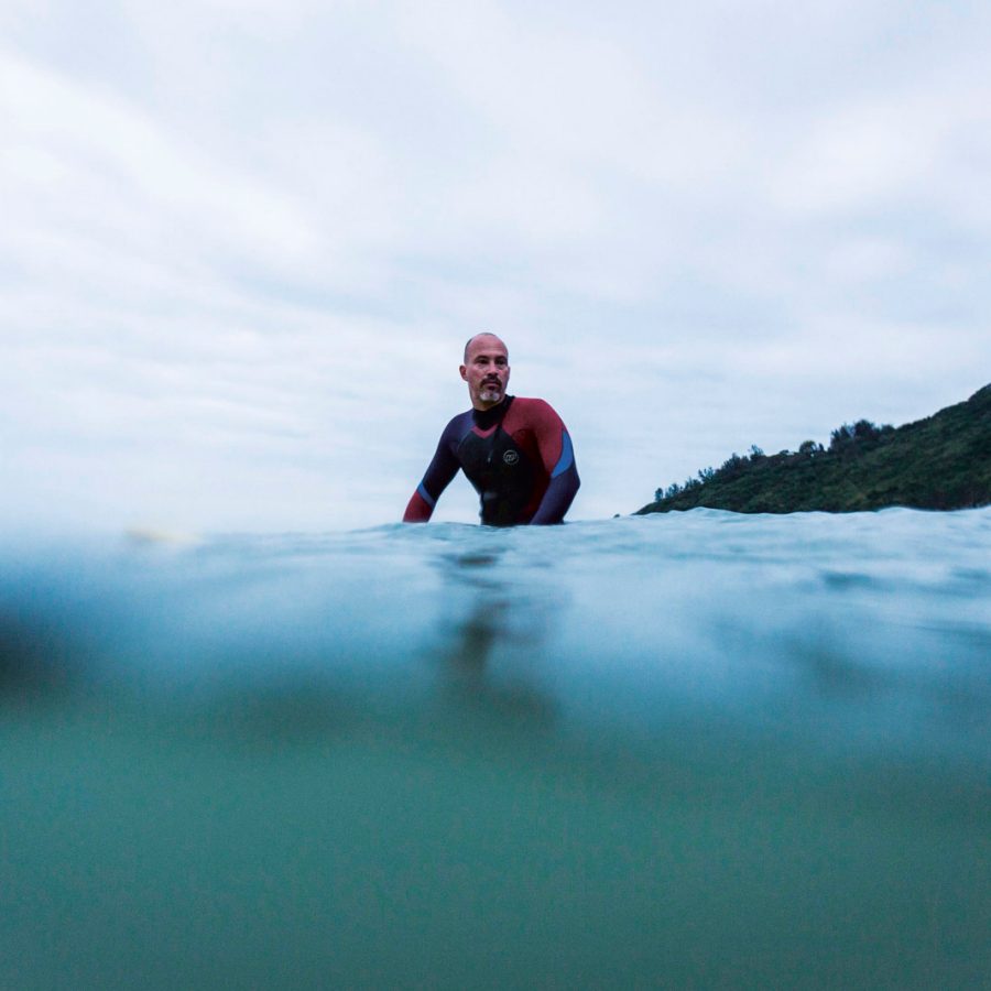 A diver runs into the water of Big Wave Bay in Hong Kong just as the sky becomes tinged with grey