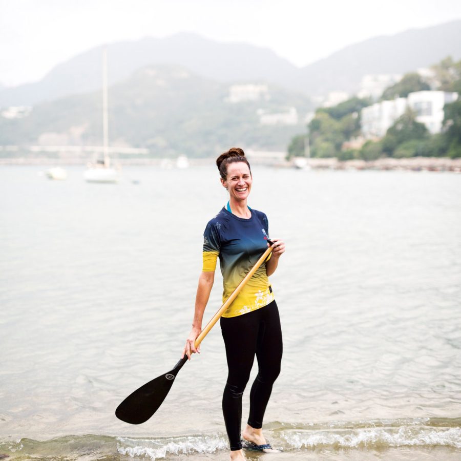 A woman smiling with a paddle at the sea in Hong Kong 