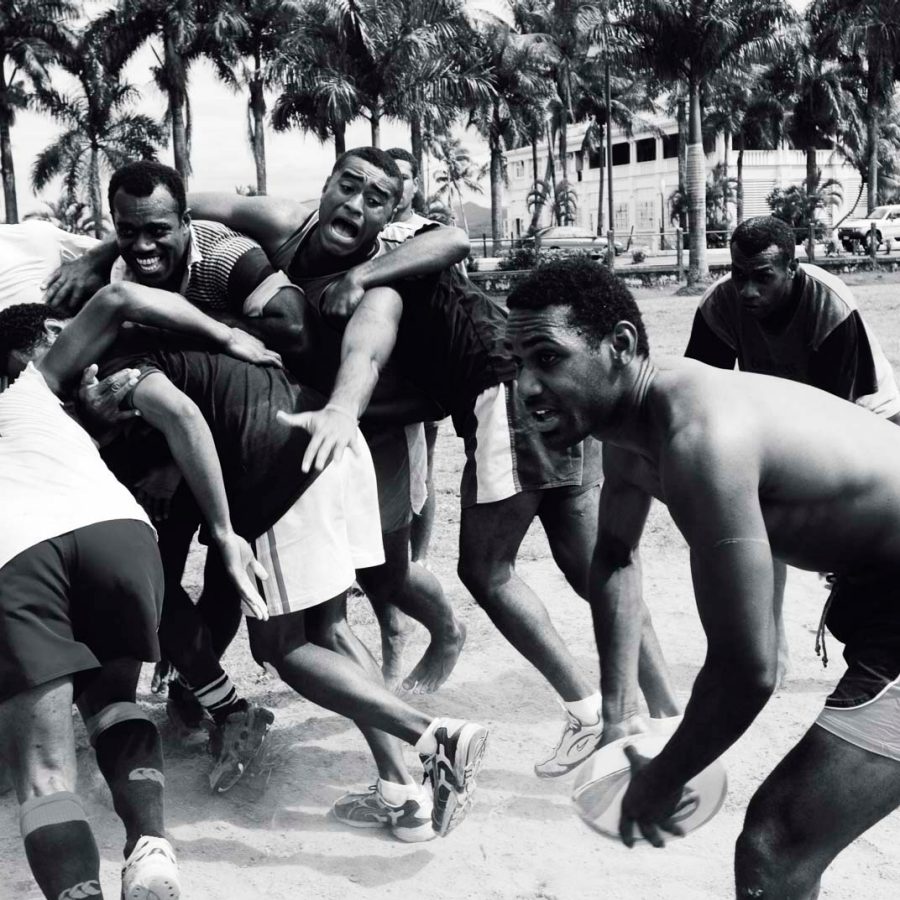 Men playing recreational rugby in park