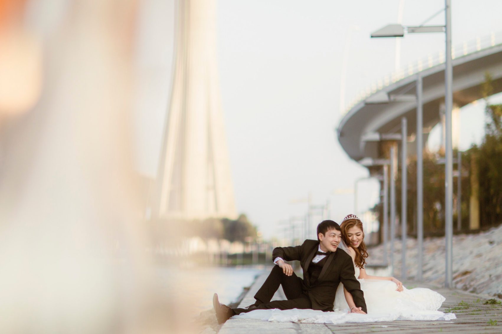 Bride and groom posing by water in Macau