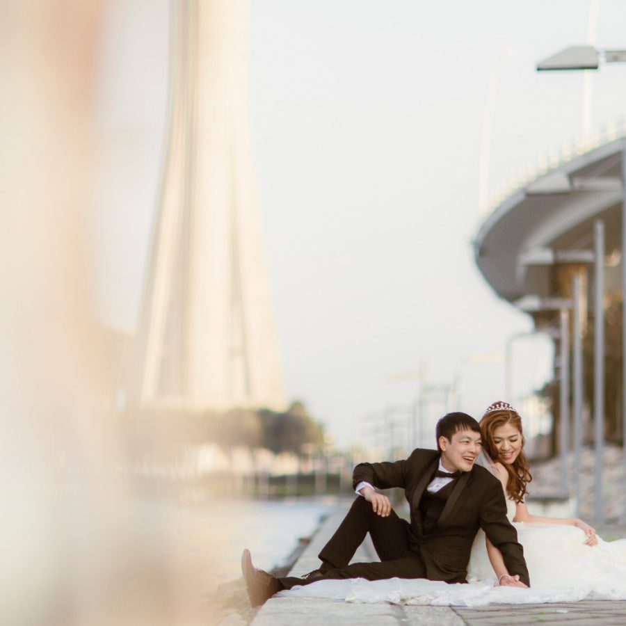 Bride and groom posing by water in Macau