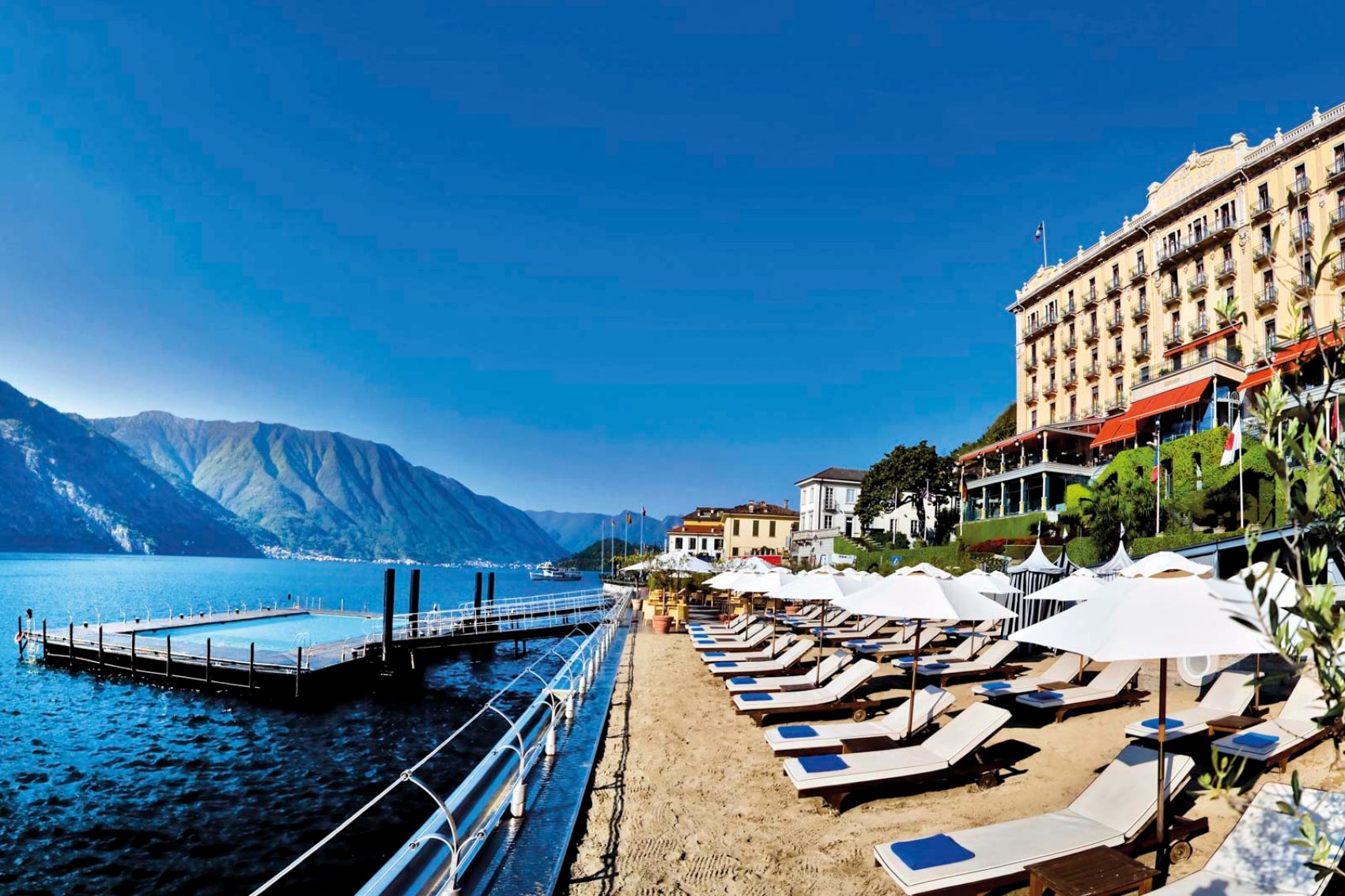 Swimming pool in the ocean with a row of deck chairs on the beach