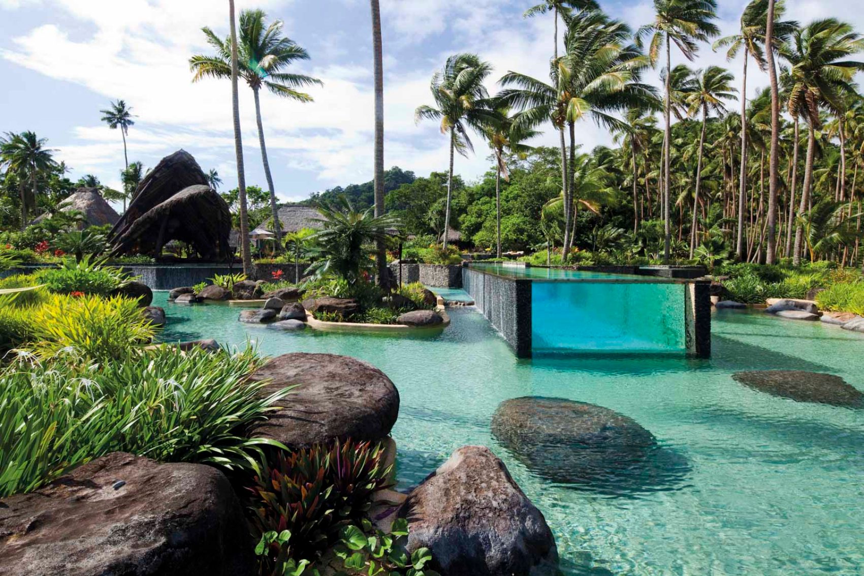 Swimming pool surrounded by a body of water and palm trees