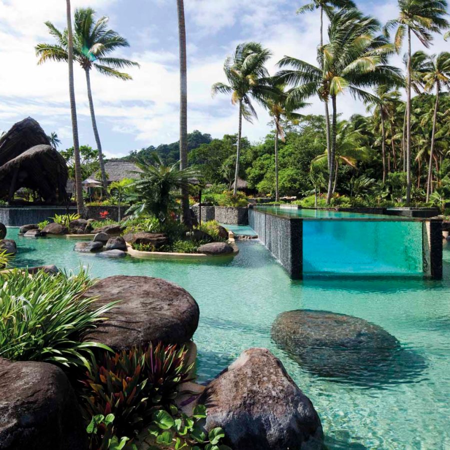 Swimming pool surrounded by a body of water and palm trees