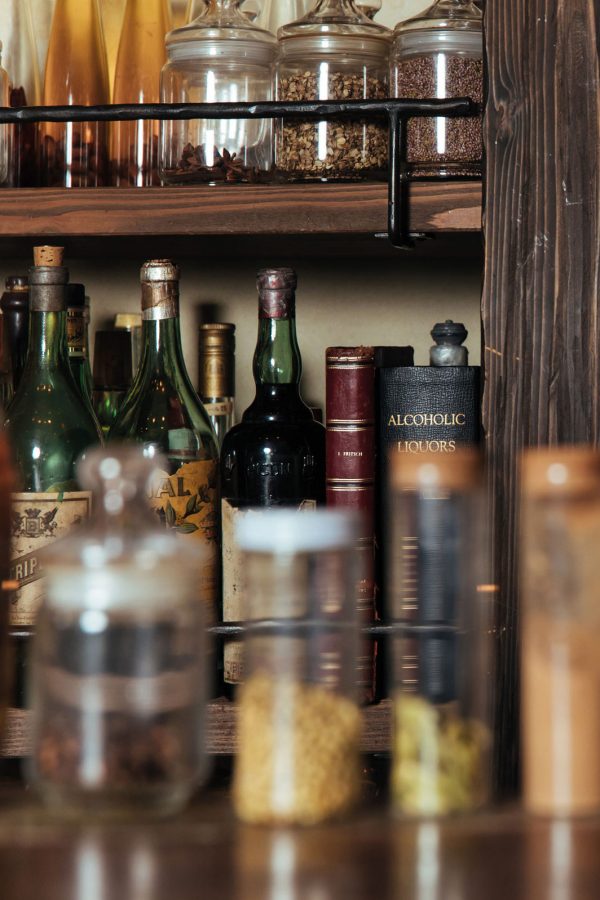 jars of yakushu infusions and dry ingredients sit above antique bottles of triple sec, absinthe and pastis