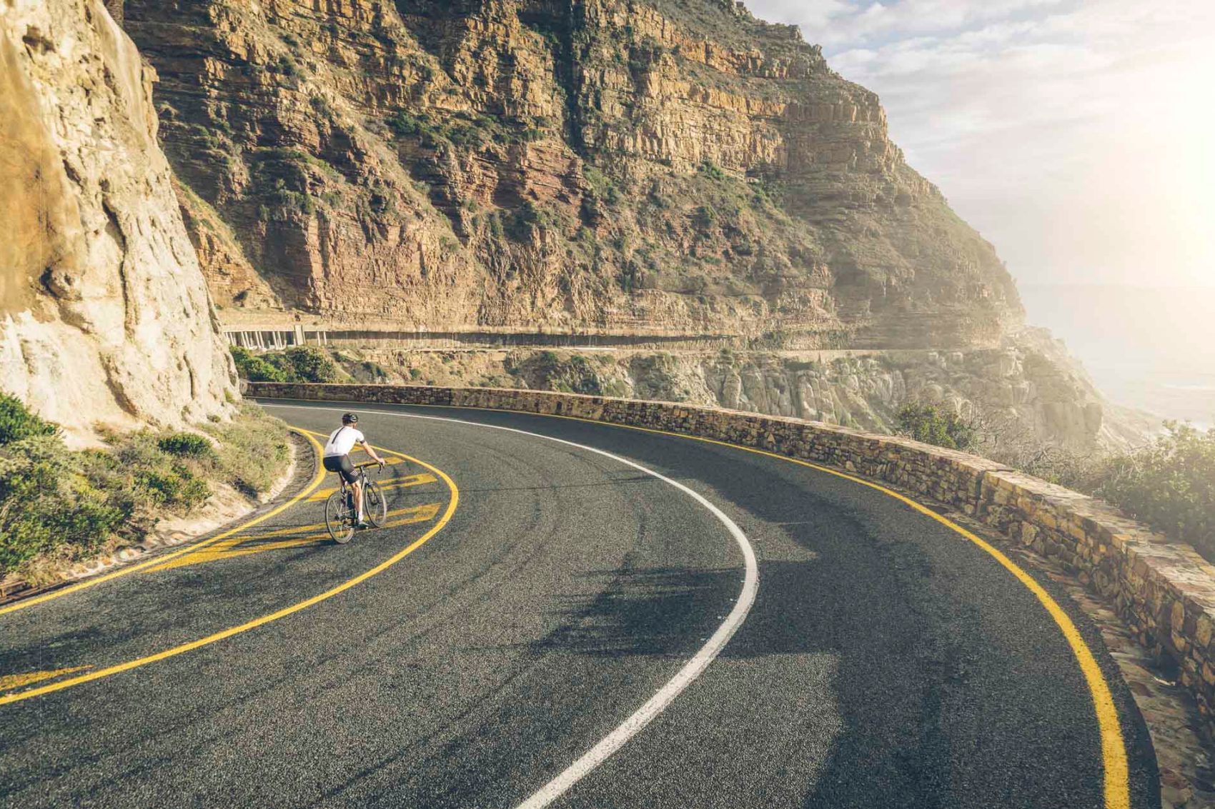 Person biking down a beautiful cliffside highway