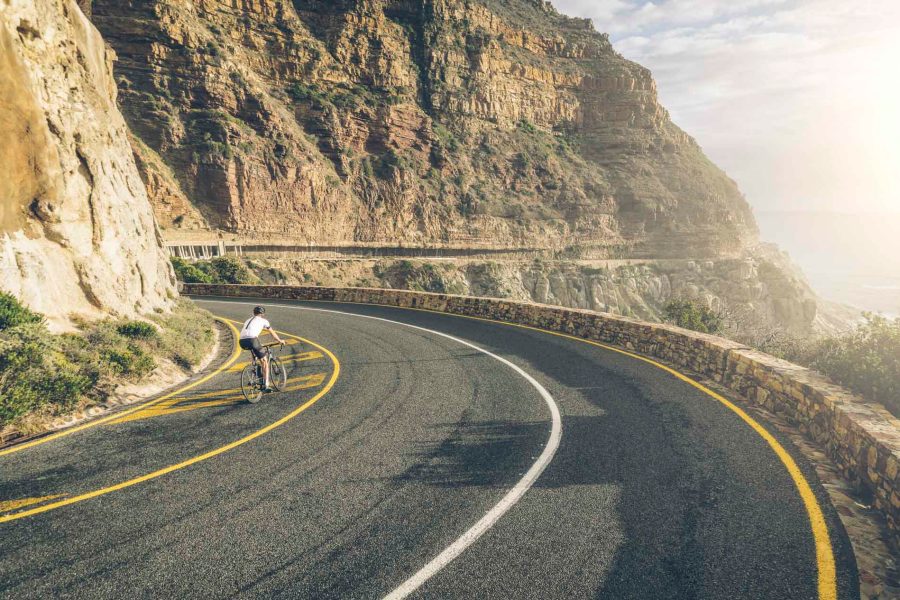 Person biking down a beautiful cliffside highway