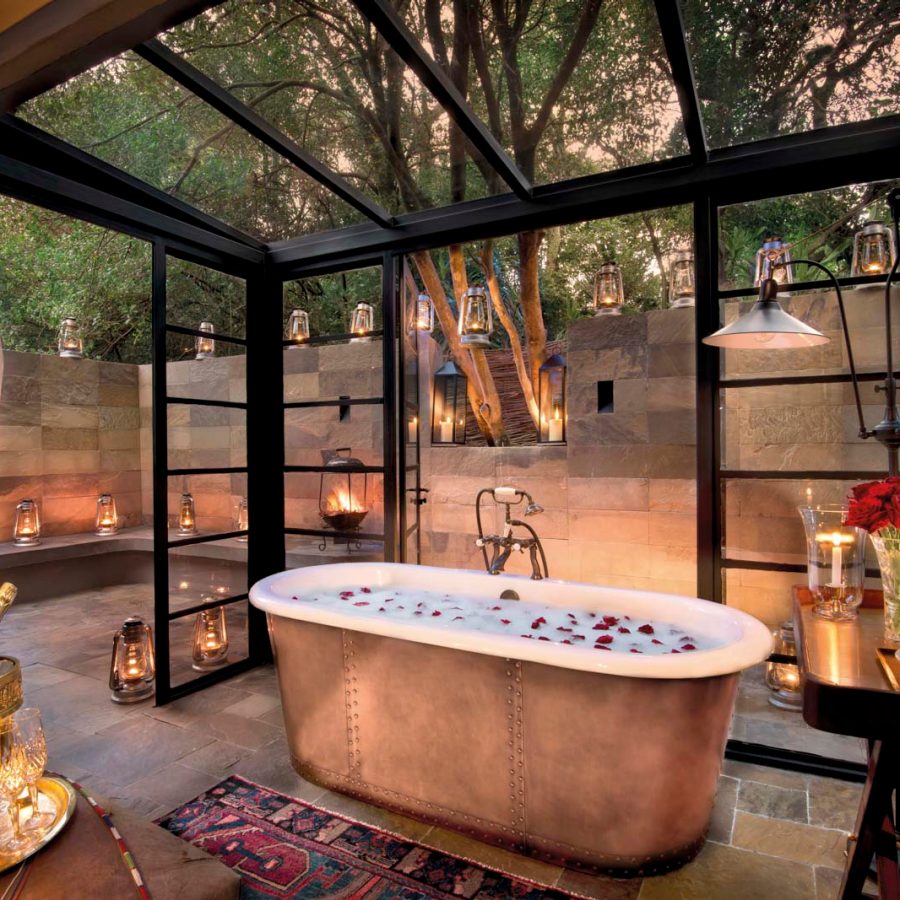 Bath tub with rose petals, surrounded by candles. 