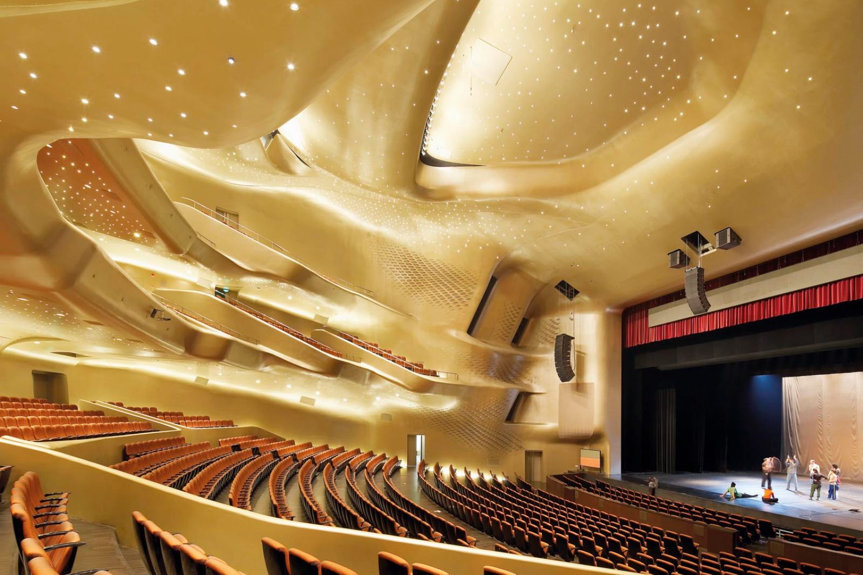 An interior view of the Guangzhou Opera House with performers rehearsing on stage