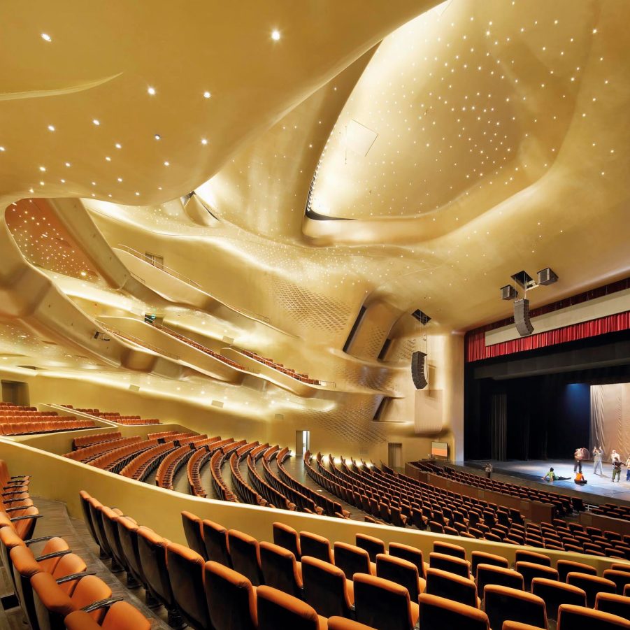 An interior view of the Guangzhou Opera House with performers rehearsing on stage