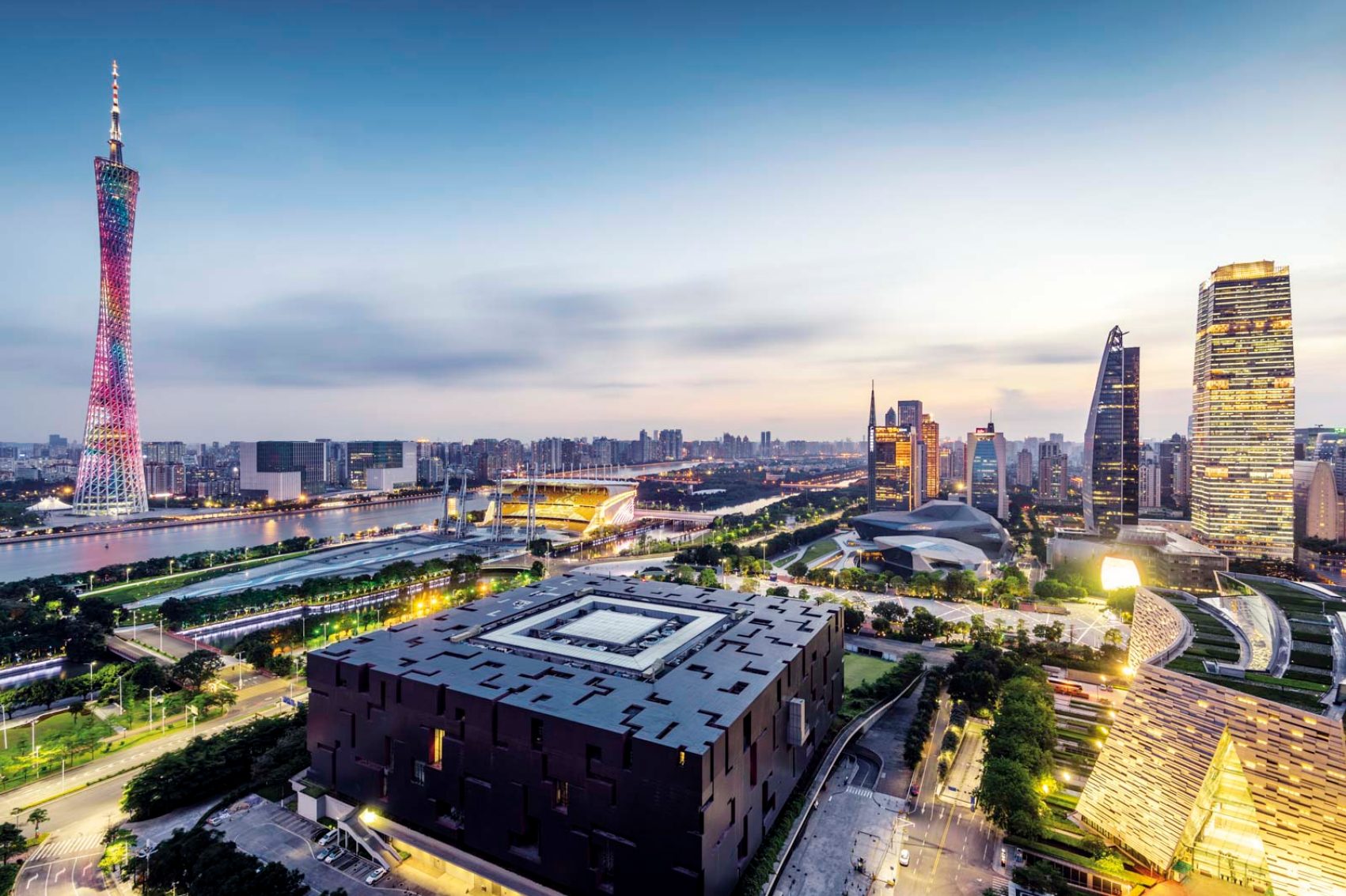 An aerial view of Guangzhou city featuring Guangdong  Museum and Canton Tower surrounded by city lights, green spaces and sky skyscrapers
