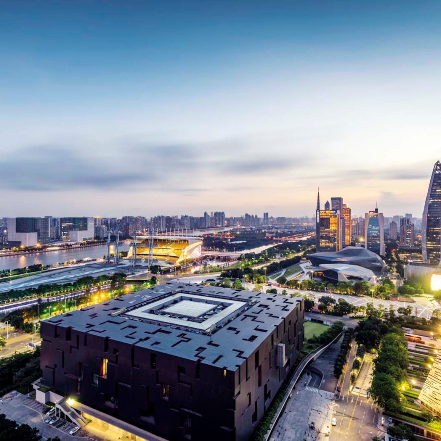 An aerial view of Guangzhou city featuring Guangdong  Museum and Canton Tower surrounded by city lights, green spaces and sky skyscrapers