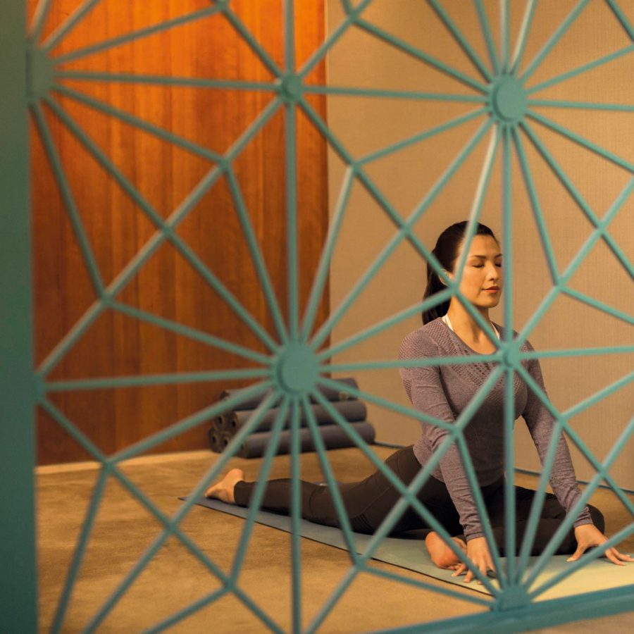 A yoga beginner is taking a spot on one of the yoga mats provided and following the onscreen instructions from Pure Yoga teachers
