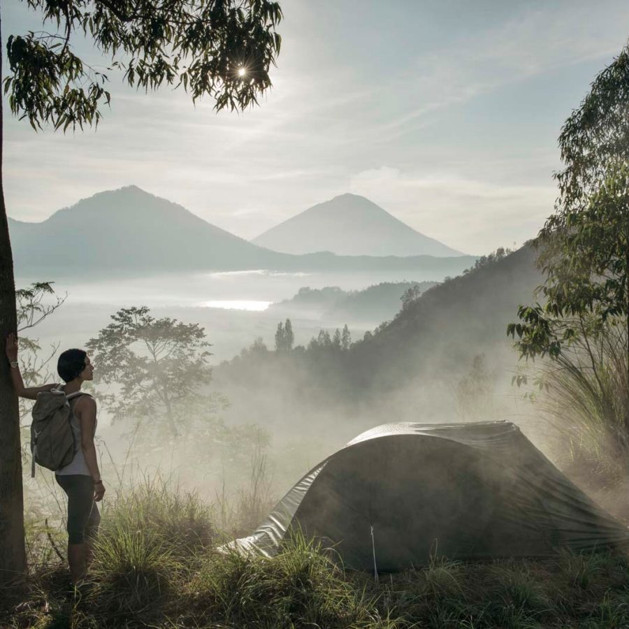 Woman standing nearby a tent over a scenic mountain view
