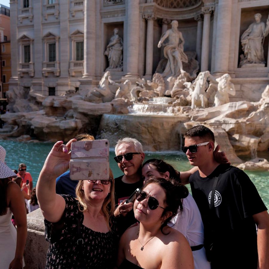 Family taking a selfie in front of Trevi Fountain in Rome