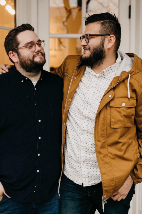 Two men standing embracing each other and smiling