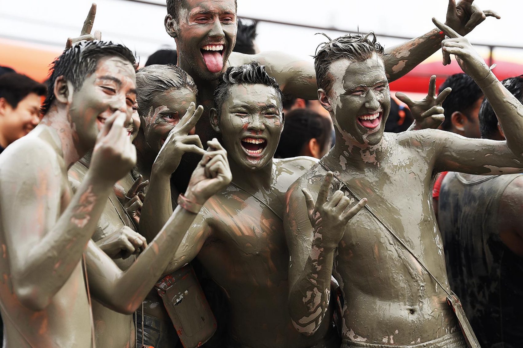 Five men covered in mud while smiling