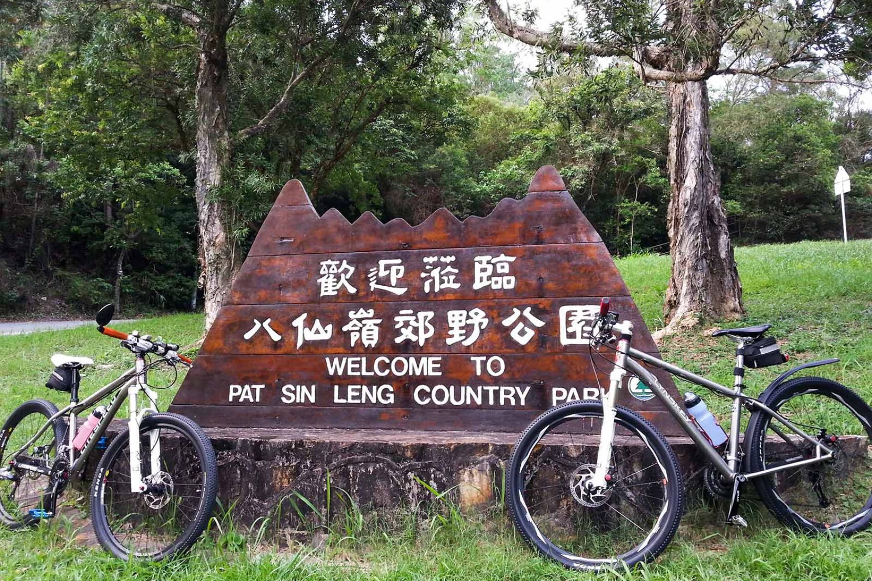 Two bicycles leaning on a wooden welcome signpost in Pat Sin Leng country park, New Territories, Hong Kong