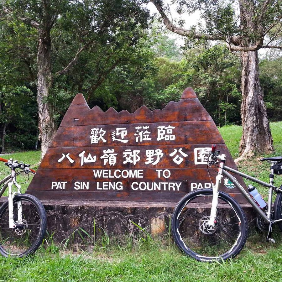 Two bicycles leaning on a wooden welcome signpost in Pat Sin Leng country park, New Territories, Hong Kong