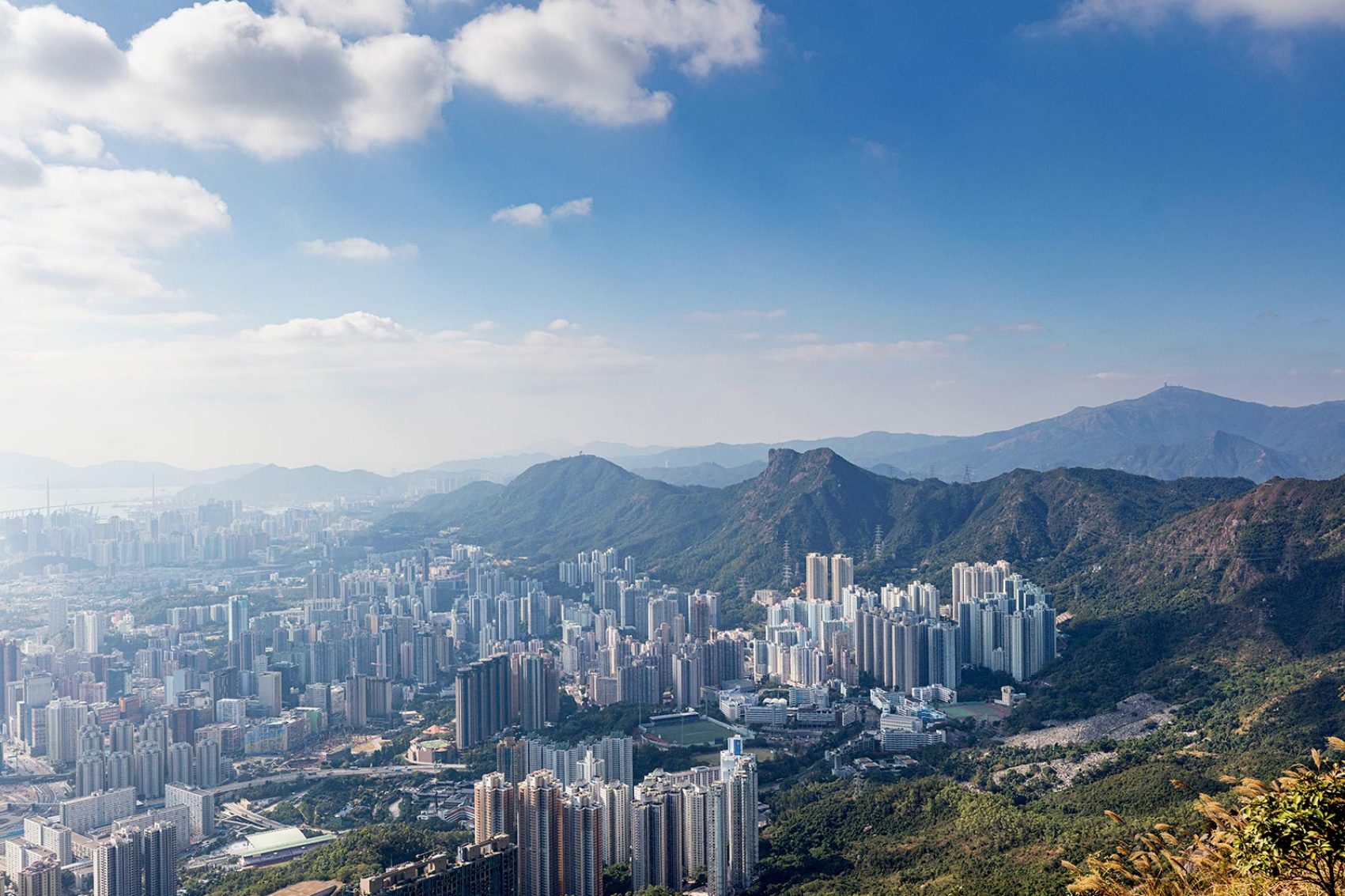 A scenic view of Hong Kong cityscape in Tate’s Cairn, New Territories surrounded by green hillsides
