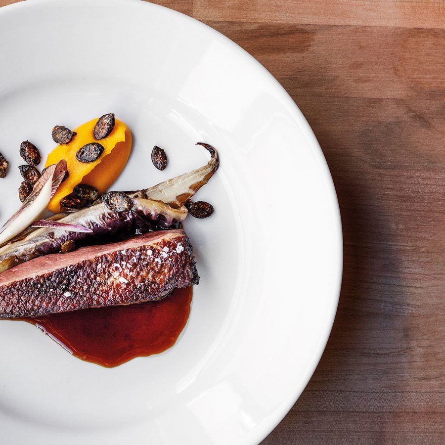 A dish is placed on a wooden table at Wermut.