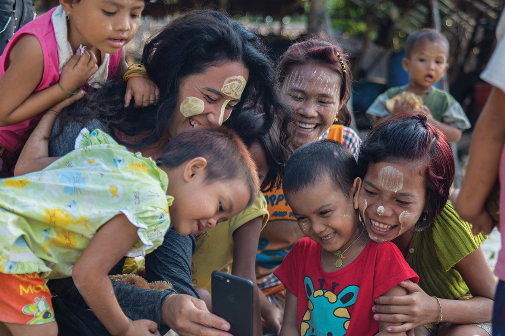Smiling children and women looking at a phone