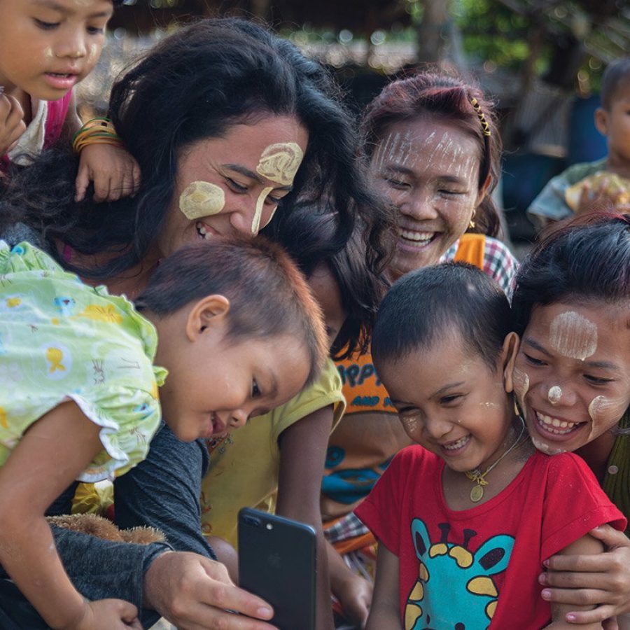 Smiling children and women looking at a phone