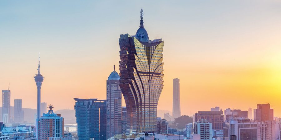 Side view of Grand Lisboa Macau and its surroundings at sunset, with a gradient of orange and blue hues in the background. 