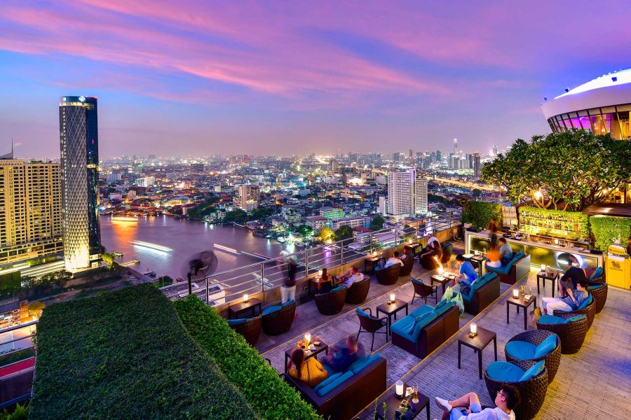 View of the Bangkok skyline at sunset from a rooftop bar.
