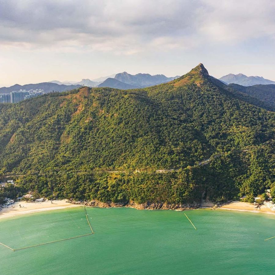 An aerial view of a beach and green hillside in High Junk Peak, New Territories, Hong Kong 